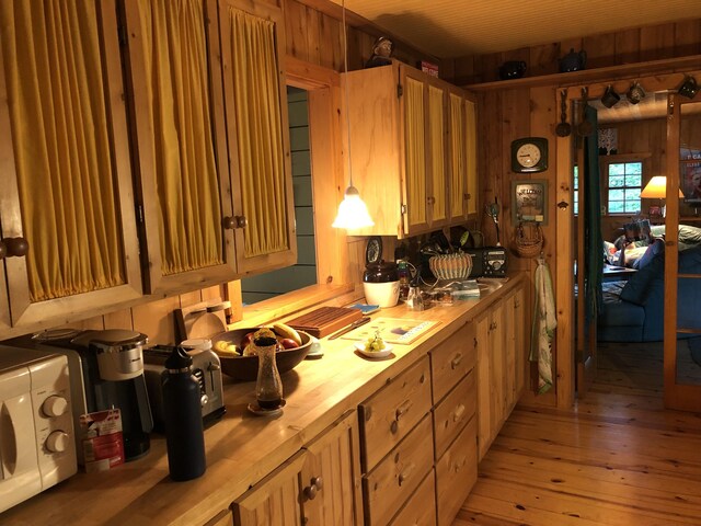 4550 E Simmons Rd, Hessel, MI 49745 - kitchen with wooden counters, light wood-style flooring, white microwave, and wood walls