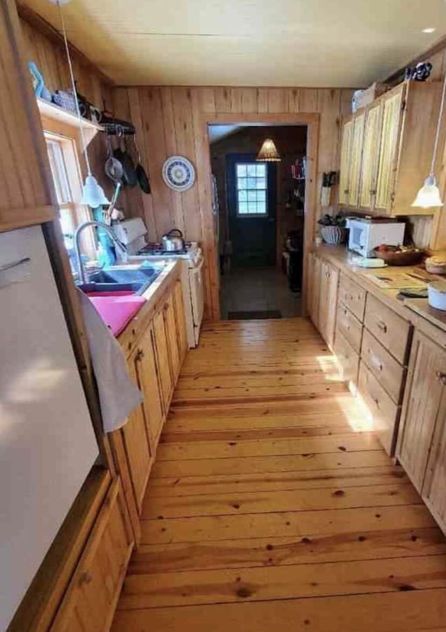 4550 E Simmons Rd, Hessel, MI 49745 - kitchen with white appliances, light wood-style flooring, a sink, wooden walls, and light countertops