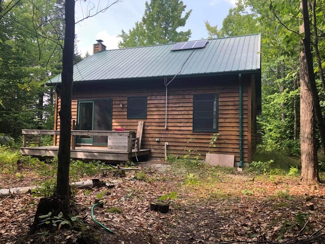 4550 E Simmons Rd, Hessel, MI 49745 - view of front of house featuring a chimney, metal roof, and a wooden deck