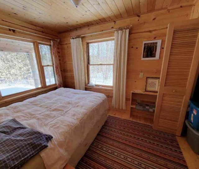 4550 E Simmons Rd, Hessel, MI 49745 - bedroom featuring wooden ceiling, multiple windows, wood walls, and light wood-style flooring