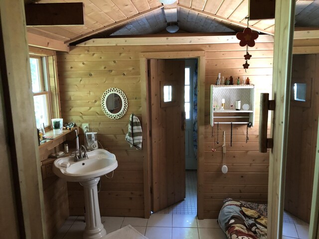 4550 E Simmons Rd, Hessel, MI 49745 - bathroom featuring wood walls, tile patterned flooring, and vaulted ceiling