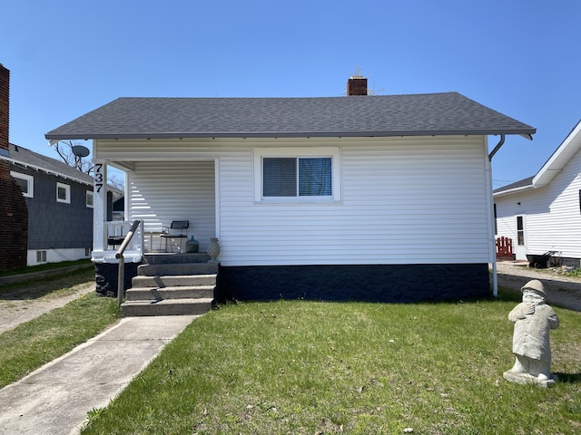 737 S First St, Rogers City, MI 49779 - view of front of home with a porch, a front lawn, a chimney, and roof with shingles