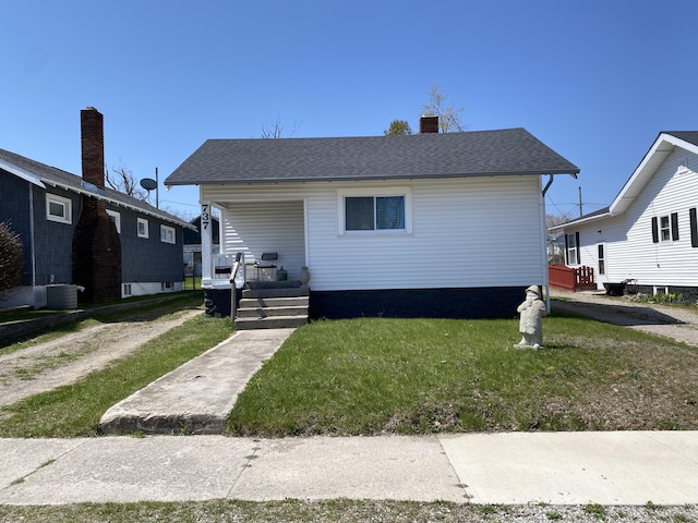 737 S First St, Rogers City, MI 49779 - bungalow with a porch, a front yard, cooling unit, and a chimney