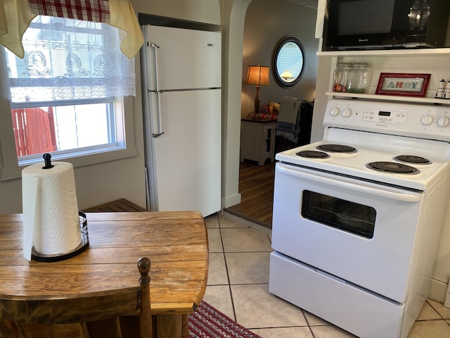 737 S First St, Rogers City, MI 49779 - kitchen featuring white appliances, arched walkways, and light tile patterned flooring
