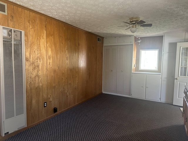 1371 Wayne Rd, Alpena, MI 49707 - unfurnished bedroom with a heating unit, wood walls, carpet flooring, a textured ceiling, and ceiling fan