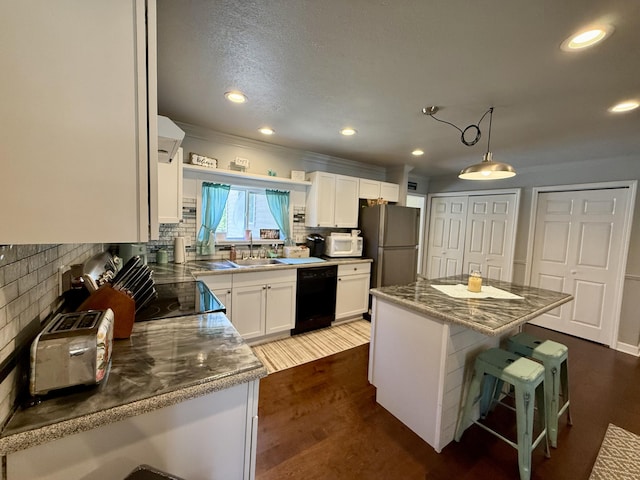 1073 S Hoot Owl Ln, Grayling, MI 49738 - kitchen with dishwasher, white microwave, tasteful backsplash, freestanding refrigerator, and white cabinets