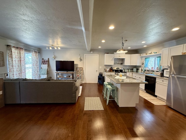 1073 S Hoot Owl Ln, Grayling, MI 49738 - kitchen featuring appliances with stainless steel finishes, a textured ceiling, open floor plan, a breakfast bar, and a kitchen island