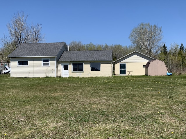 back of property with a yard and a shingled roof