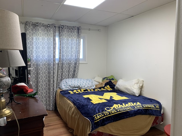 bedroom with light wood-type flooring and a drop ceiling
