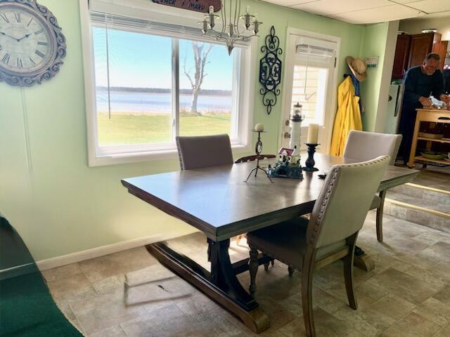 dining area featuring baseboards, a water view, and a chandelier