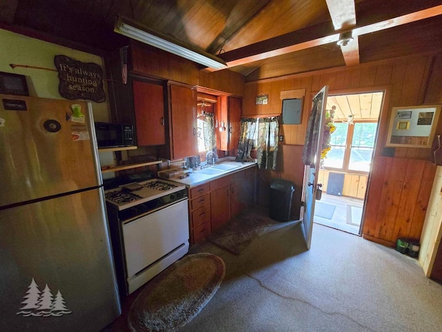 4097 Sunset Dr, Lewiston, MI 49756 - kitchen with freestanding refrigerator, gas range gas stove, black microwave, wood walls, and a sink