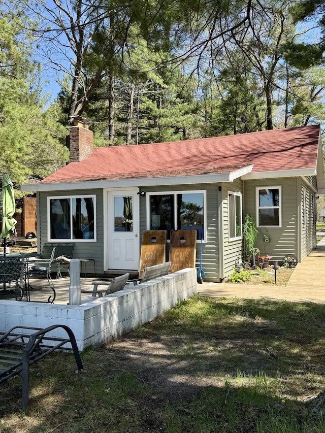 6299 Woodland Dr, Oscoda, MI 48750 - back of house featuring a chimney and roof with shingles