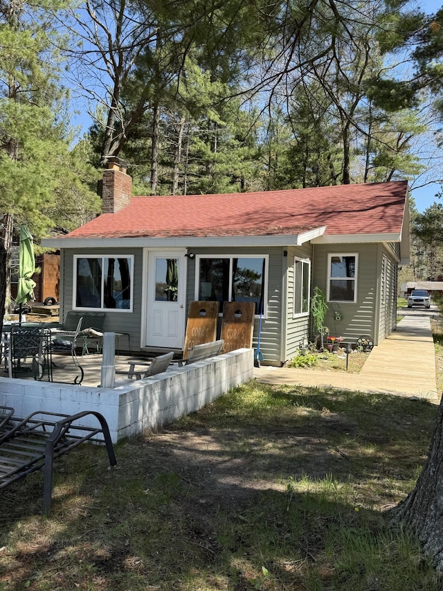 6299 Woodland Dr, Oscoda, MI 48750 - rear view of property featuring a chimney and a shingled roof