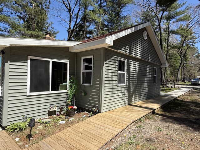 6299 Woodland Dr, Oscoda, MI 48750 - view of side of property featuring a wooden deck and a chimney