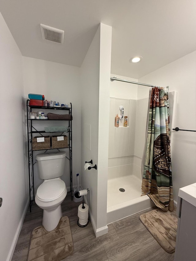 6299 Woodland Dr, Oscoda, MI 48750 - full bath with wood finished floors, a shower stall, toilet, and baseboards