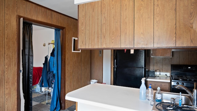 3182 W Houghton Lake Dr, Houghton Lake, MI 48629 - kitchen with freestanding refrigerator, wood walls, light countertops, a sink, and brown cabinetry