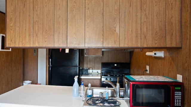 3182 W Houghton Lake Dr, Houghton Lake, MI 48629 - kitchen with black appliances, brown cabinetry, and light countertops