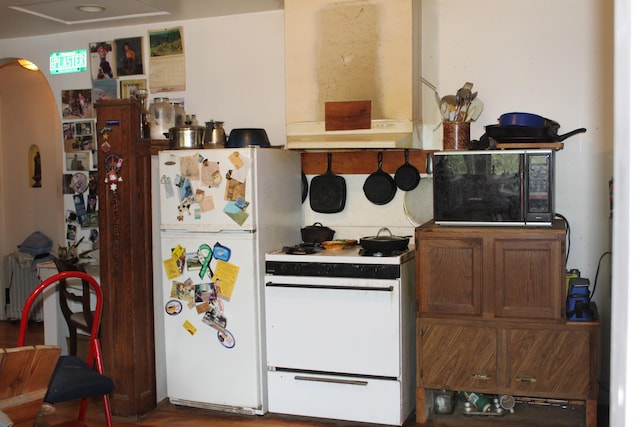 2032 W Oak Rd, Luzerne, MI 48636 - kitchen with white appliances, arched walkways, and custom exhaust hood