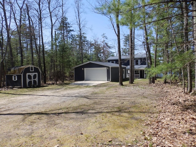 7928 Blueberry Ln, Johannesburg, MI 49751 - view of front of home with an outdoor structure, a storage shed, dirt driveway, and an attached garage