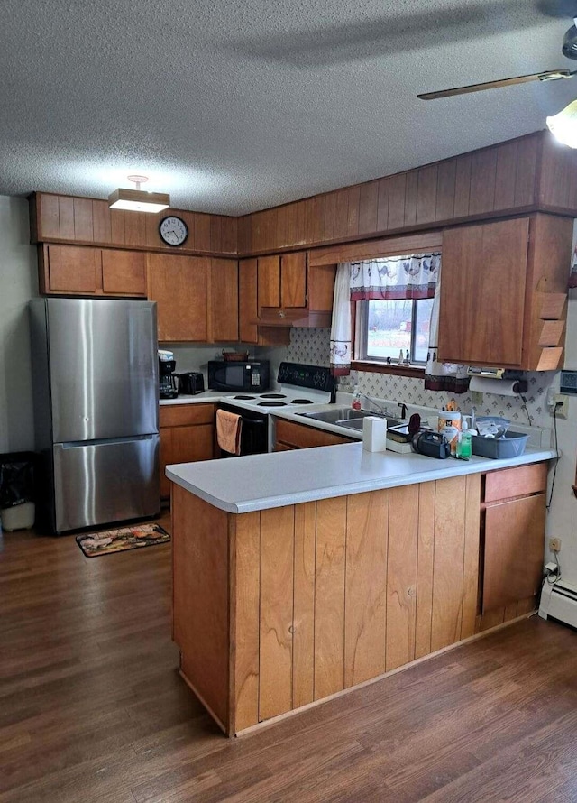 2056 N M-65, Lachine, MI 49753 - kitchen featuring freestanding refrigerator, range with electric stovetop, black microwave, brown cabinets, and dark wood-type flooring