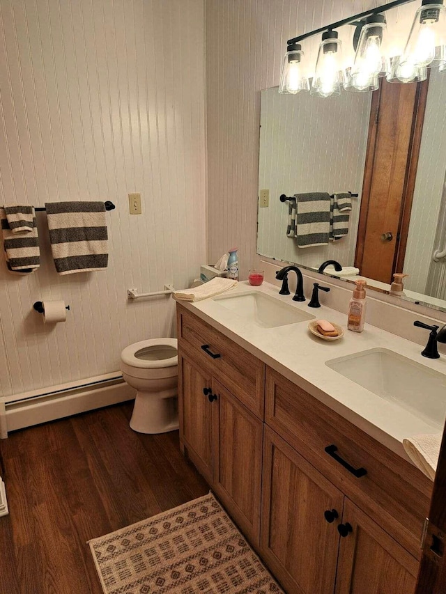 2056 N M-65, Lachine, MI 49753 - bathroom featuring baseboard heating, toilet, wood finished floors, and double vanity