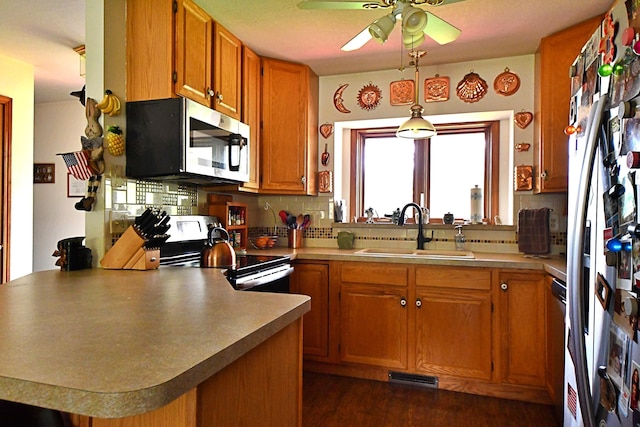 4930 Warrington Way, Gladwin, MI 48624 - kitchen with stainless steel appliances, a sink, a peninsula, ceiling fan, and tasteful backsplash