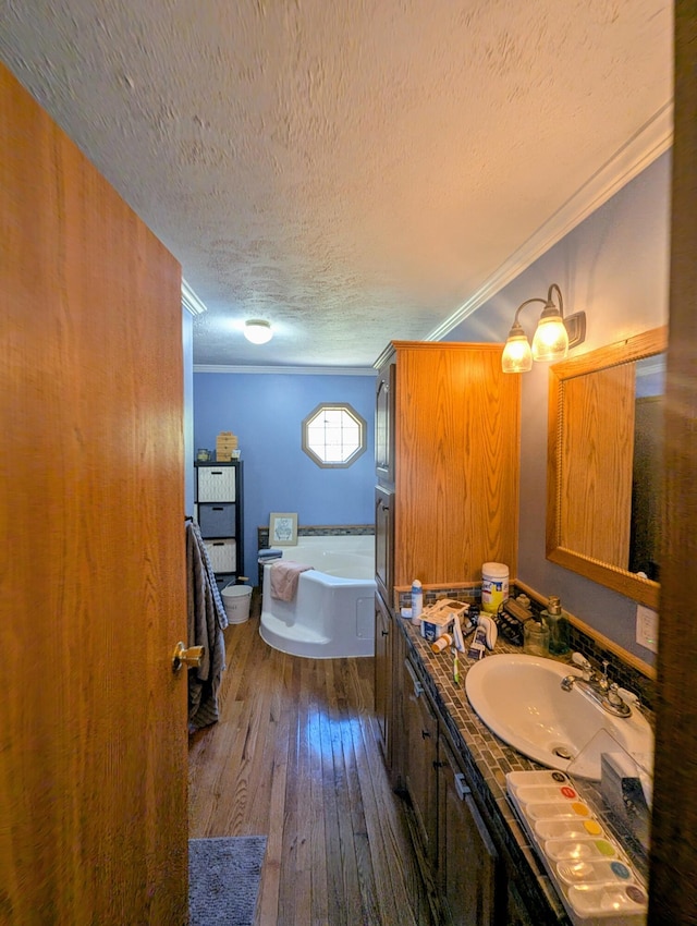 9367 Clewley Rd, Lachine, MI 49753 - bathroom featuring a textured ceiling, vanity, a garden tub, hardwood / wood-style flooring, and crown molding