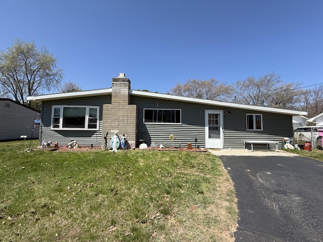 view of front facade with a chimney, a front lawn, and driveway