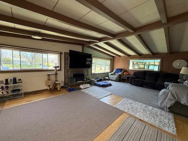 living area with healthy amount of natural light, wood finished floors, and a stone fireplace