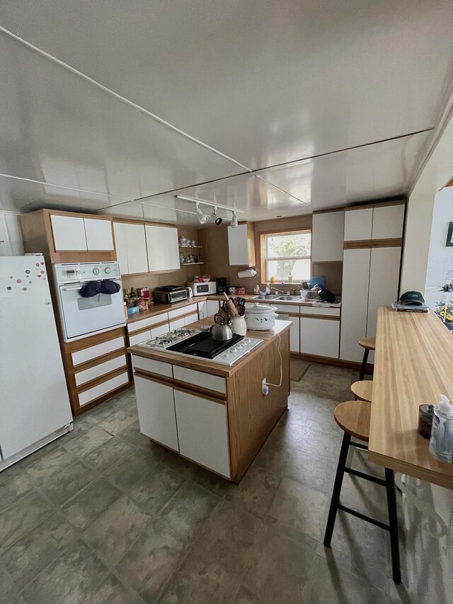 20417 State St, Onaway, MI 49765 - kitchen with white appliances, white cabinets, a center island, and light countertops