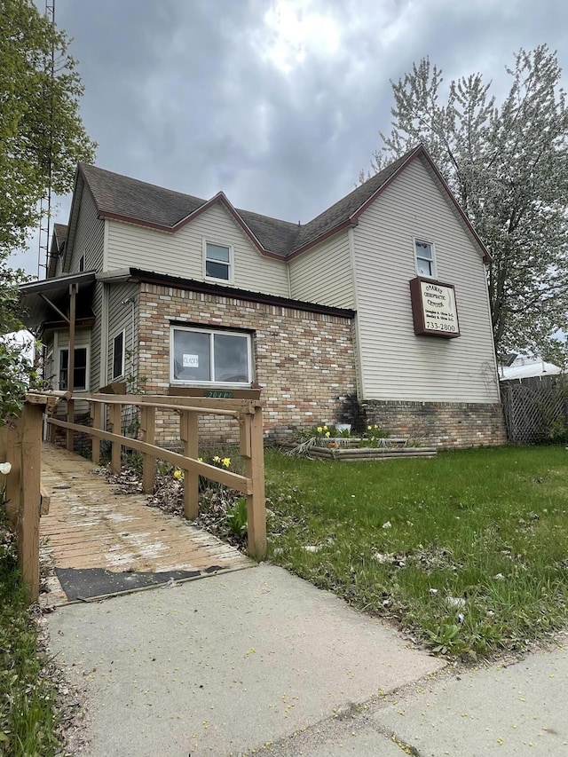 20417 State St, Onaway, MI 49765 - view of front facade featuring brick siding, fence, and a shingled roof