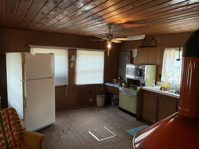 kitchen featuring freestanding refrigerator, wooden ceiling, a sink, wood walls, and a ceiling fan