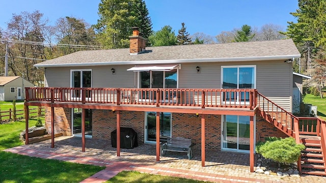 back of property with stairway, a patio, a wooden deck, a chimney, and a lawn