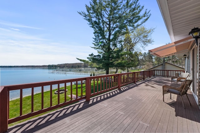 wooden terrace featuring a water view and a lawn