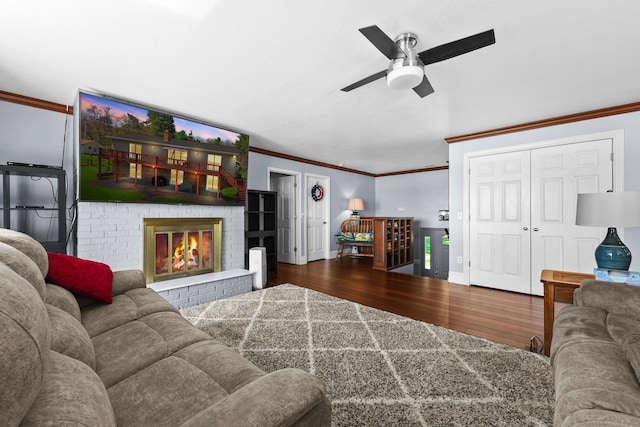 living room with ornamental molding, wood finished floors, a ceiling fan, a fireplace, and baseboards