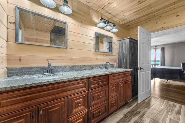 full bath featuring wooden walls, wood finished floors, wooden ceiling, and double vanity