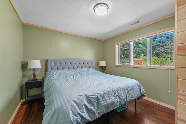 bedroom with baseboards, hardwood / wood-style flooring, crown molding, and a textured ceiling