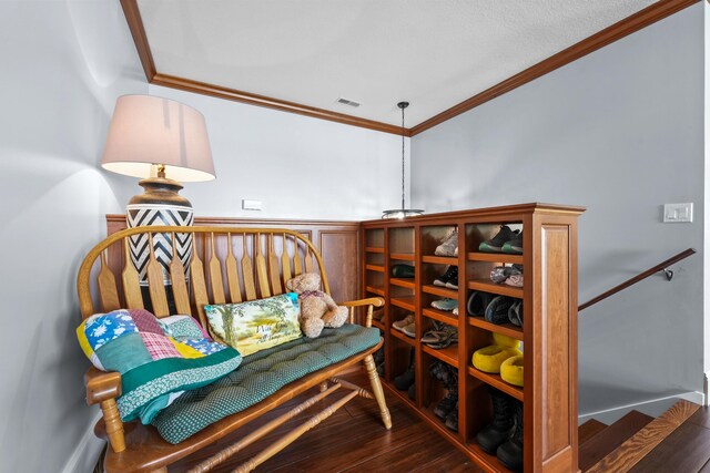 living area featuring crown molding, wood finished floors, and wainscoting