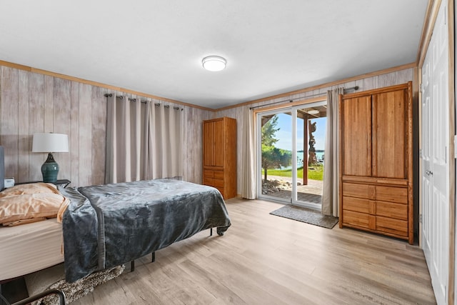 bedroom featuring access to outside, wood walls, light wood finished floors, and crown molding