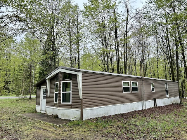 8448 Heatherton Cir, Mancelona, MI 49659 - view of home's exterior with metal roof and a view of trees