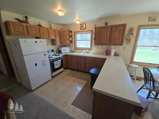 4795 Bruce Dr, Lewiston, MI 49756 - kitchen featuring white appliances, brown cabinets, a sink, a peninsula, and open shelves