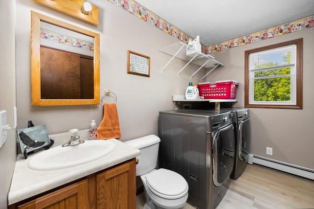 11758 Woodview Trl, Gaylord, MI 49735 - bathroom featuring independent washer and dryer, wood finished floors, a baseboard heating unit, vanity, and toilet