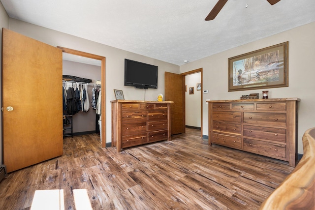 11758 Woodview Trl, Gaylord, MI 49735 - bedroom featuring wood finished floors, a closet, a walk in closet, baseboards, and ceiling fan