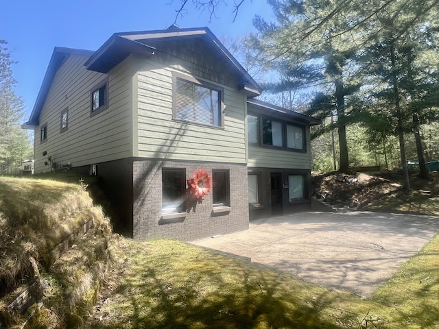 6475 W Legner Trl, Grayling, MI 49738 - back of property with a patio area, concrete driveway, and brick siding