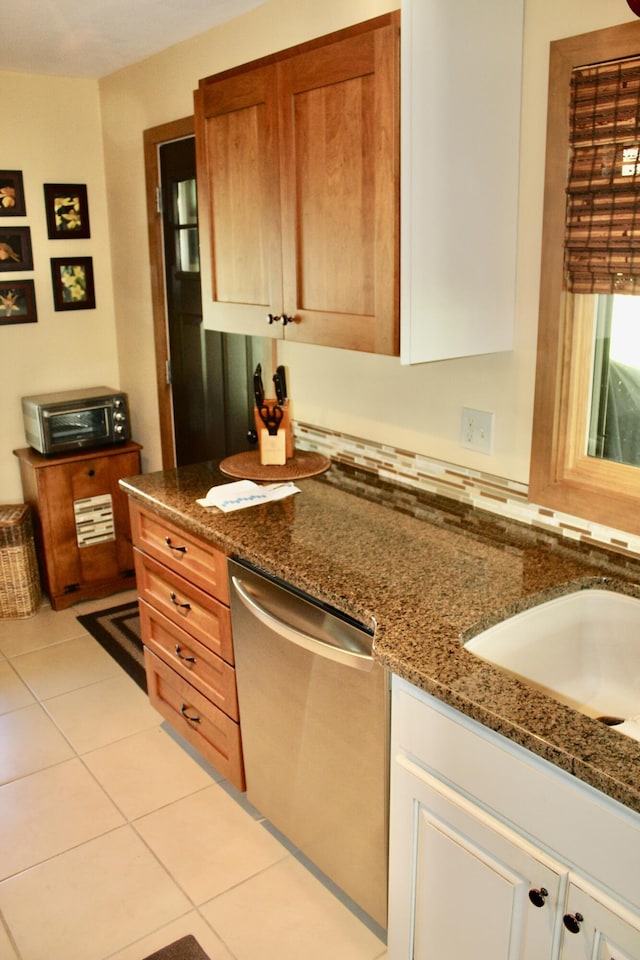 6475 W Legner Trl, Grayling, MI 49738 - kitchen featuring stainless steel dishwasher, dark stone countertops, a sink, and light tile patterned floors