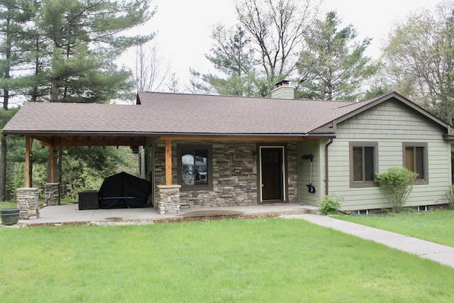 6475 W Legner Trl, Grayling, MI 49738 - ranch-style house with a front yard, a chimney, a shingled roof, a porch, and stone siding