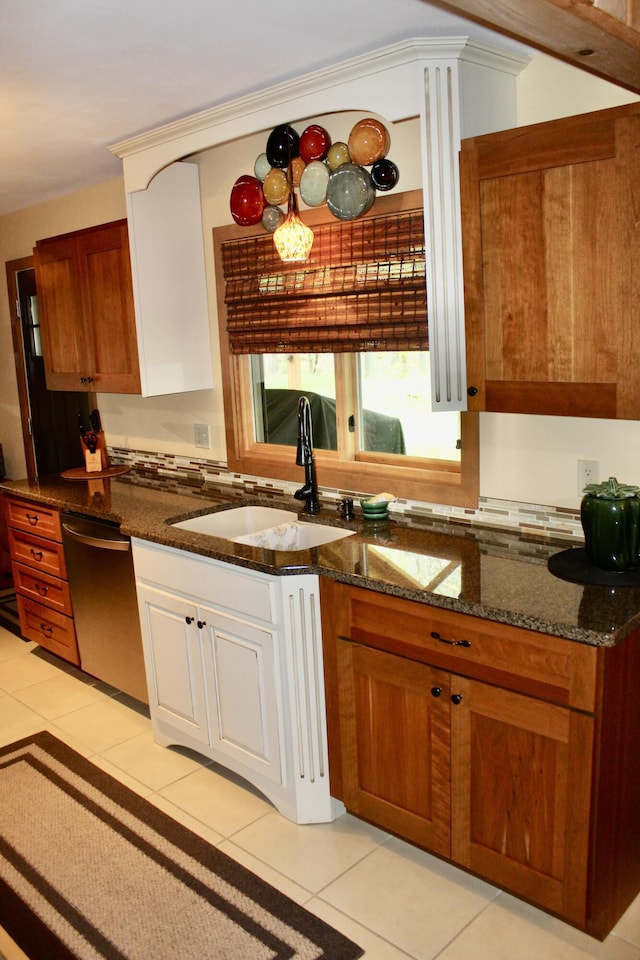 6475 W Legner Trl, Grayling, MI 49738 - kitchen with a sink, stainless steel dishwasher, light tile patterned floors, dark stone countertops, and brown cabinetry