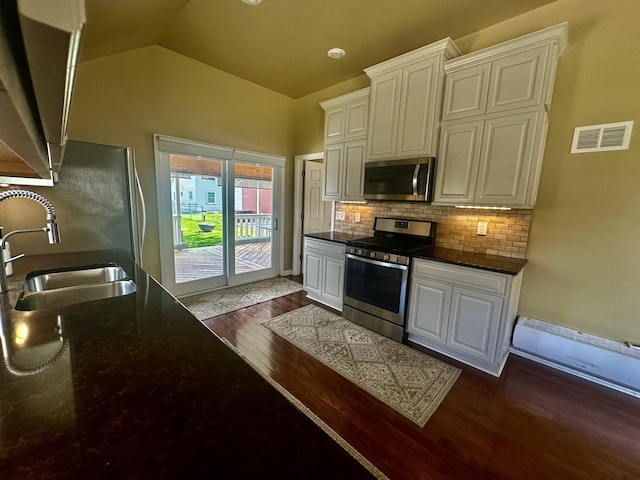 kitchen with stainless steel appliances, dark wood-type flooring, a sink, white cabinets, and lofted ceiling