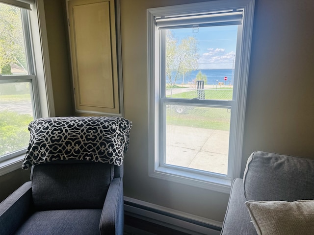 sitting room featuring a baseboard radiator, healthy amount of natural light, and a water view