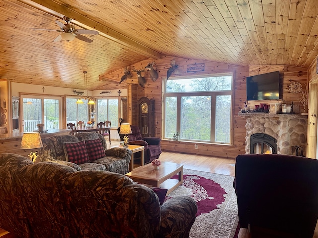 870 Dalton Dr, Rose City, MI 48654 - living room featuring wooden walls, wood finished floors, a ceiling fan, wooden ceiling, and a stone fireplace